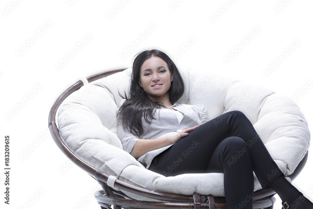 Modern young woman sitting in a round cozy soft chair Modern young woman sitting in a round cozy soft chair