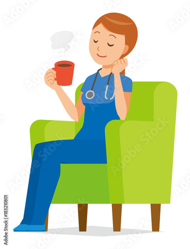 A woman nurse in a blue scrub is sitting on a sofa and drinking coffee