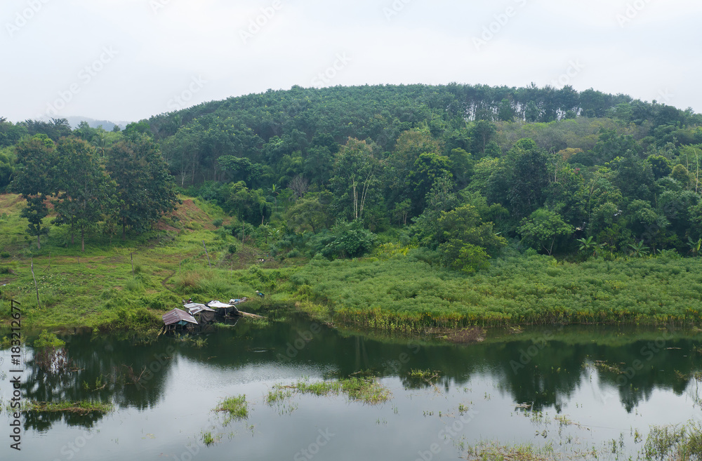 Fototapeta premium Landscape of river and green forest mountain with wooden house at Kanchanaburi, Thailand