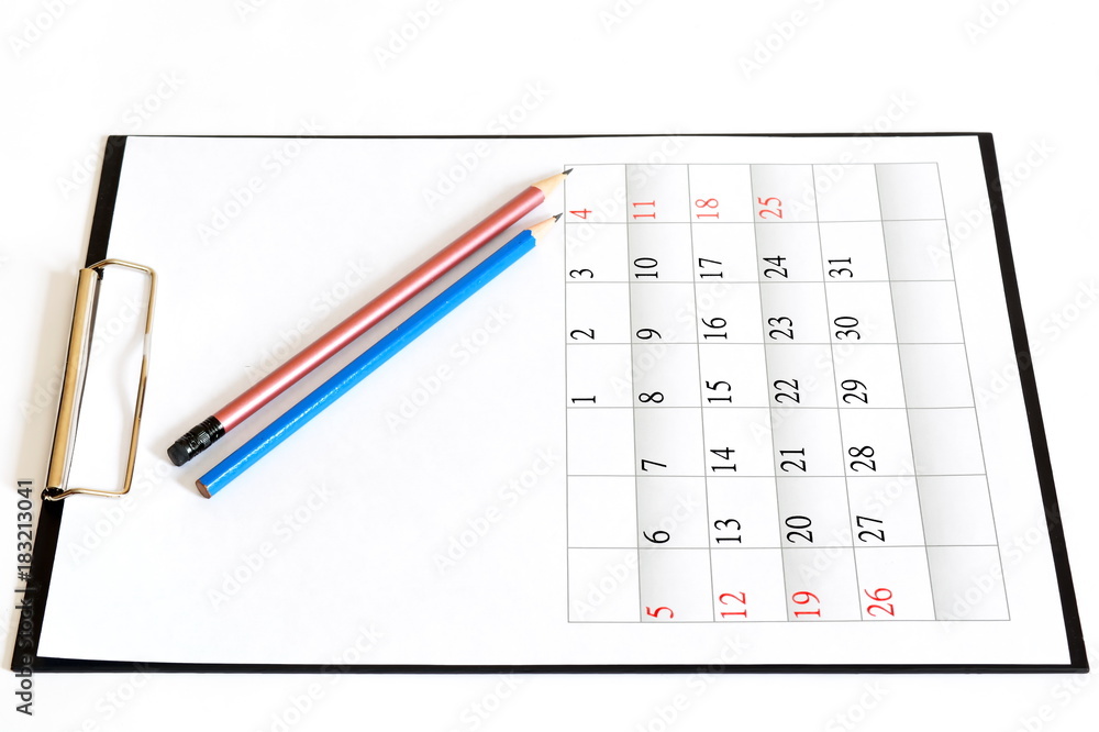 Two pencils on black clipboard with clean sheet of month paper calendar. Isolated. White background Two pencils on black clipboard with clean sheet of month paper calendar. Isolated. White background