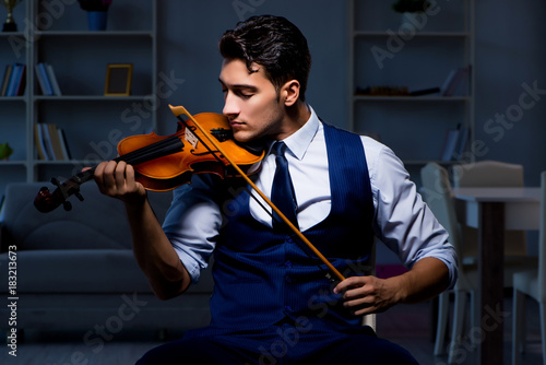 Young musician man practicing playing violin at home