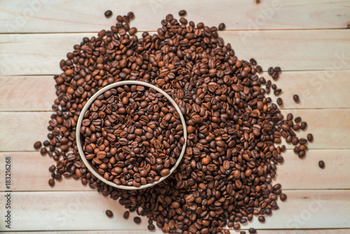 Big porcelain pot filled with coffee beans on wooden table. Place for text. Menu design. Top view.