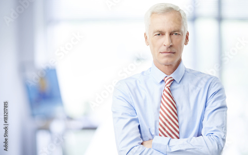 Financial business man. A senior financial consultant businessman standing in shirt and tie in his office.