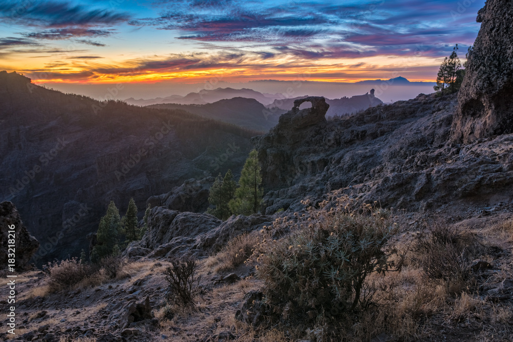 spectacular sunset over roque nublo mountain on Gran Canaria, in the background visible volcano Teide on tenerife