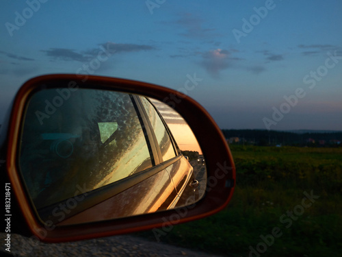 Young man photographing sunset from the car on full speed