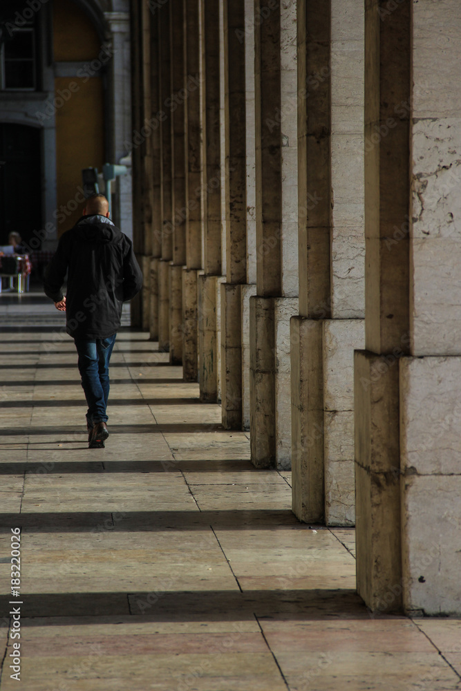 Man walkin in a stone archway around the Praça do Comércio in the center of Lisbon, Portugal Man walkin in a stone archway around the Praça do Comércio in the center of Lisbon, Portugal
