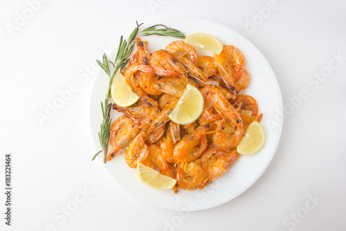 Fried prawns on a white plate. Shrimp fried in oil with garlic and lemon on a plate.