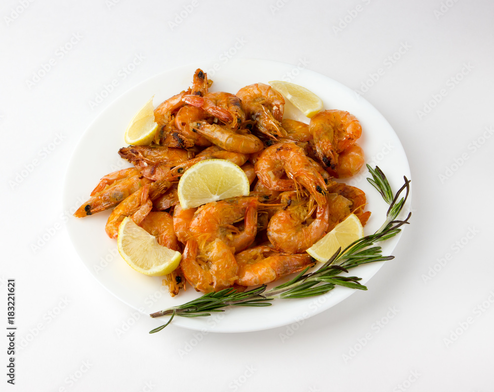 Fried prawns on a white plate. Shrimp fried in oil with garlic and lemon on a plate. Fried prawns on a white plate. Shrimp fried in oil with garlic and lemon on a plate.
