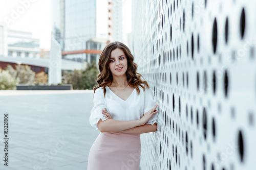 Office style. A business portrait of the young woman in a white blouse and a pink skirt against the background of city architecture. Free Download Office style. A business portrait of the young woman in a white blouse and a pink skirt against the background of city architecture. - GFXLoad
