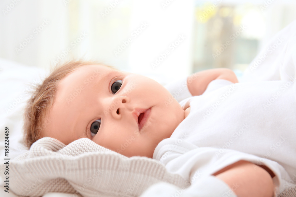 Cute little baby lying on bed at home