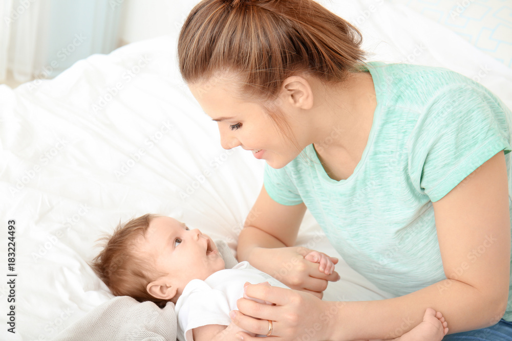Young mother and cute baby on bed at home Young mother and cute baby on bed at home