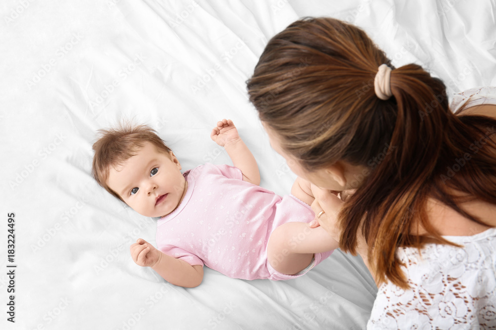 Mother playing with cute baby on bed at home Mother playing with cute baby on bed at home