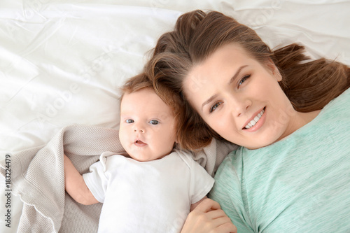 Young mother and cute baby on bed at home