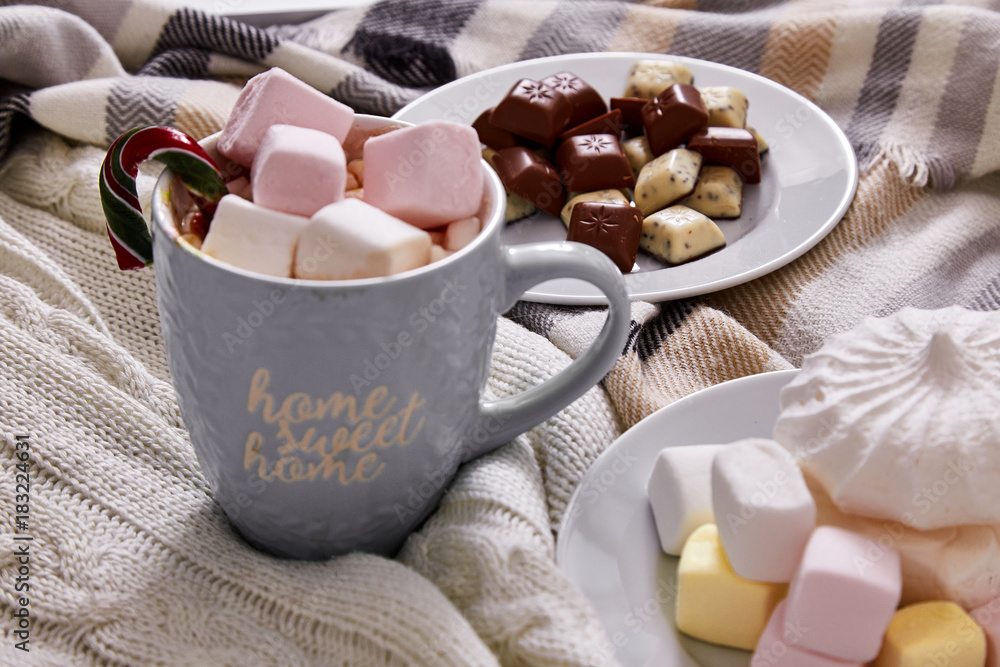 Winter mood composition Christmas Day at home with cup of hot cacao or coffee with marshmallow sweets candy cane and chocolate in the bed with wool knitted plaid New Year. Winter mood composition Christmas Day at home with cup of hot cacao or coffee with marshmallow sweets candy cane and chocolate in the bed with wool knitted plaid New Year.