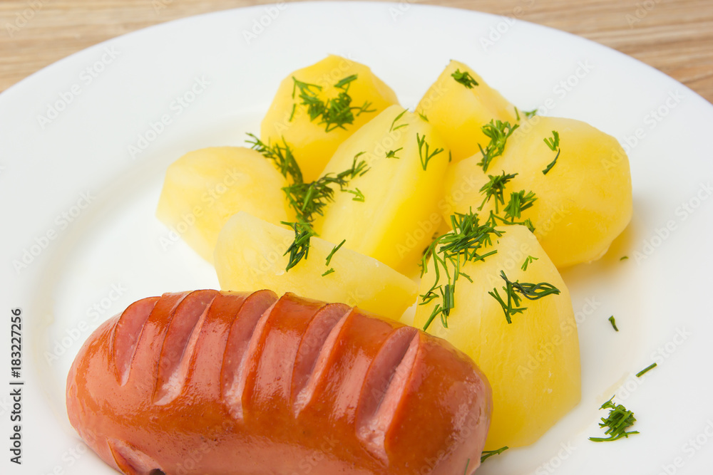 Fried sausage with boiled potatoes. A dish of boiled potatoes and fried sausages on a white plate. Fried sausage with boiled potatoes. A dish of boiled potatoes and fried sausages on a white plate.