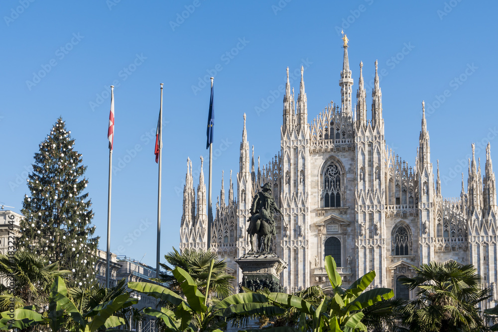 Milan, Italy: view of Duomo square with palm garden, Christmas tree and the cathedral facade in a sunny day of december.