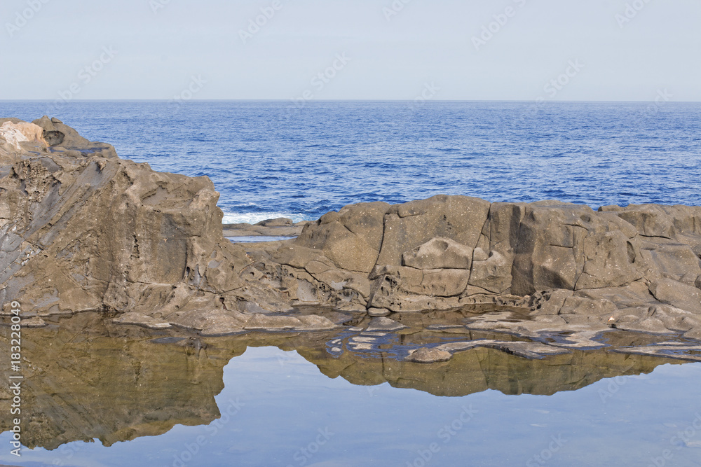 Smooth rocks reflected in the motionless water.