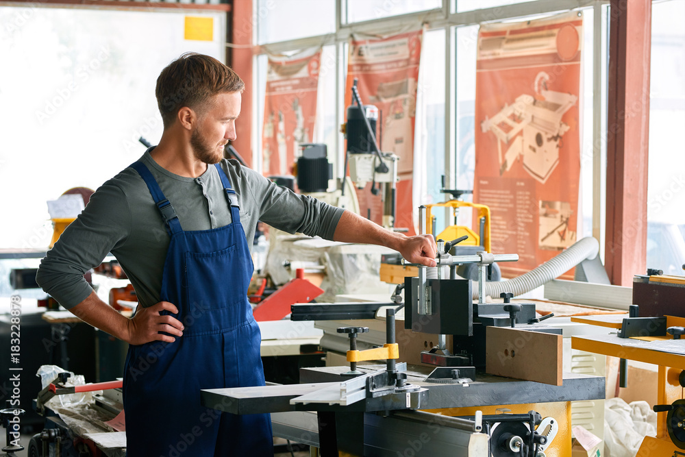 Portrait of young worker inspecting machine units in workshop of modern factory, copy space Portrait of young worker inspecting machine units in workshop of modern factory, copy space