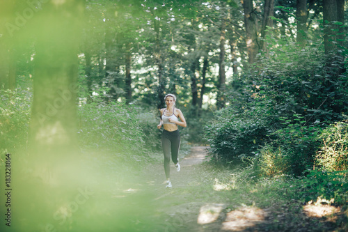 Attractive blonde  fitness woman running in the morning wood