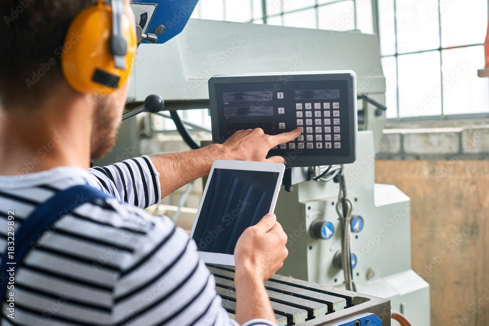 Back view portrait of factory worker operating machines at modern factory using digital tablet with electronic control, copy space Back view portrait of factory worker operating machines at modern factory using digital tablet with electronic control, copy space