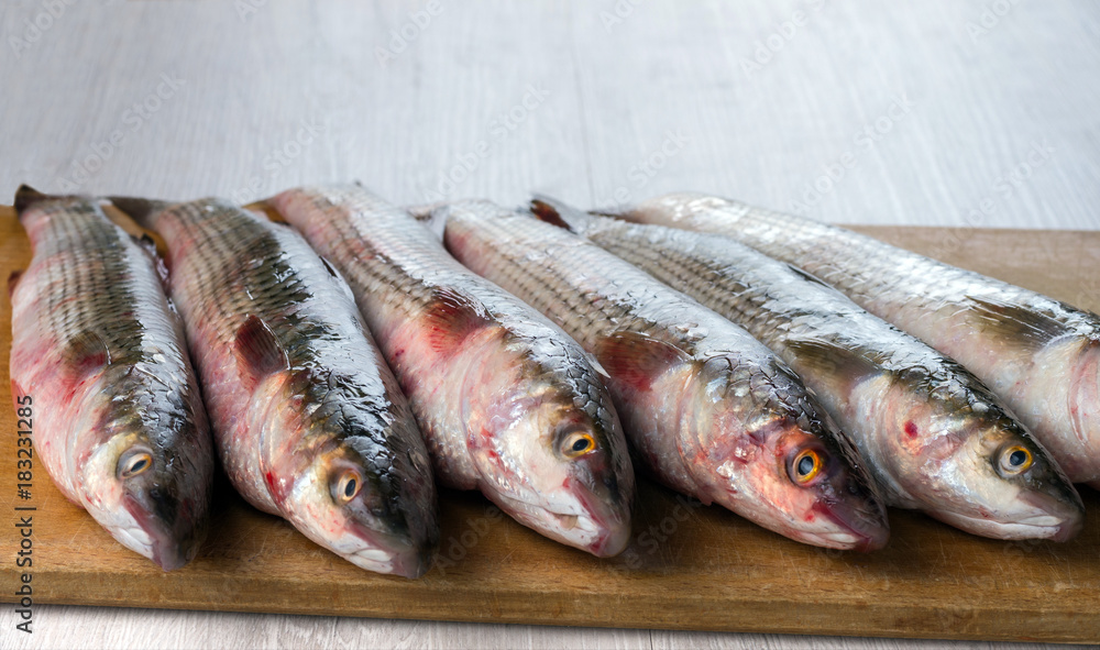 Fresh mullet fish on a cutting board.