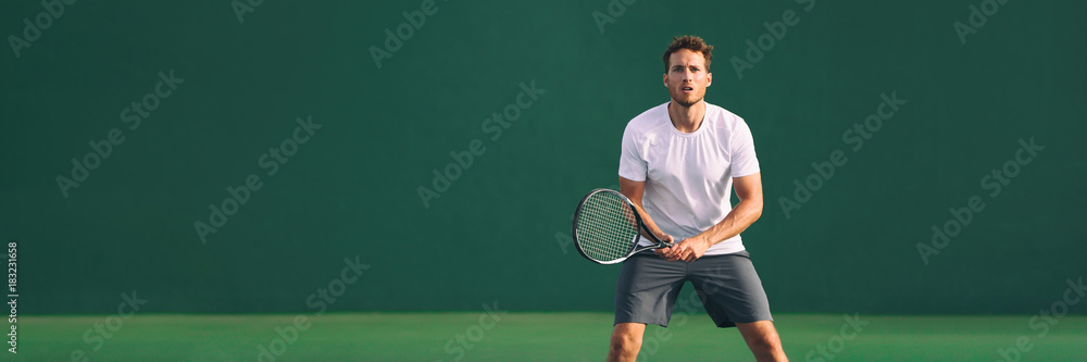 Tennis player man focused in ready position. A male athlete waiting for serve on panoramic green background banner. Challenge and concentration in competition.