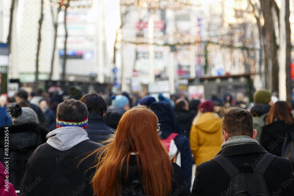 A red haired girl walking down the crowded street