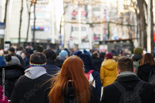 A red haired girl walking down the crowded street