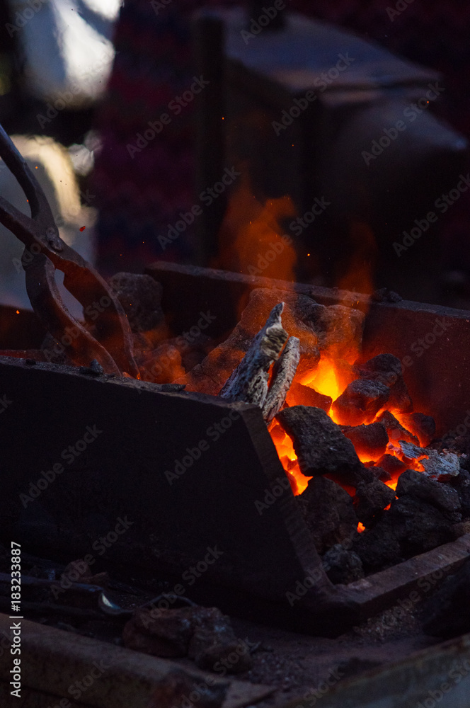 blacksmith furnace with burning coals, tools, and glowing hot metal workpieces