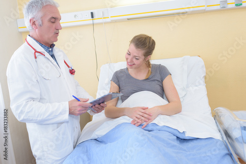 senior doctor with clipboard visiting woman at hospital ward