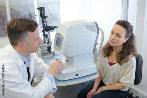 male optometrist checking female patient vision at eye clinic