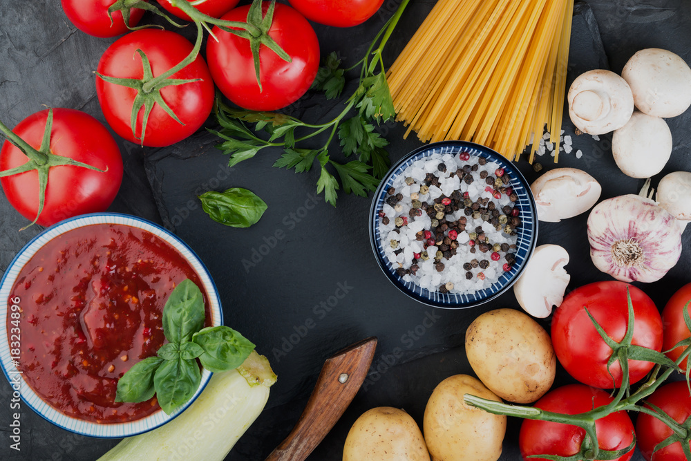 Italian pasta and tomatoes, ingredients for cooking on dark background. Top view
