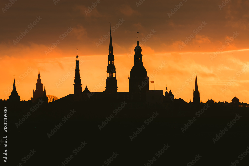 City silhouette of Riga, Latvia in colorful morning sunset. Church towers and popular landmarks in background with stunning yellow sky. 