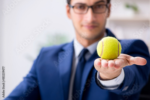 Young businessman with tennis ball working in office © Elnur