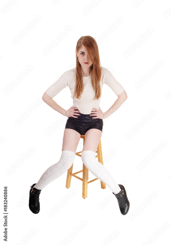 Beautiful woman sitting in shorts an heels on chair