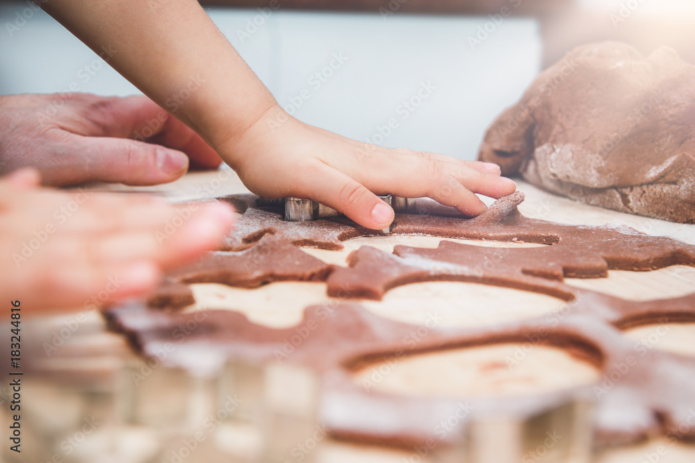 Baking gingerbreads. The family is preparing a gingerbread. The boy is reflecting the mold. Preparing for Christmas, time for the family, cooking together and baking the concept. 