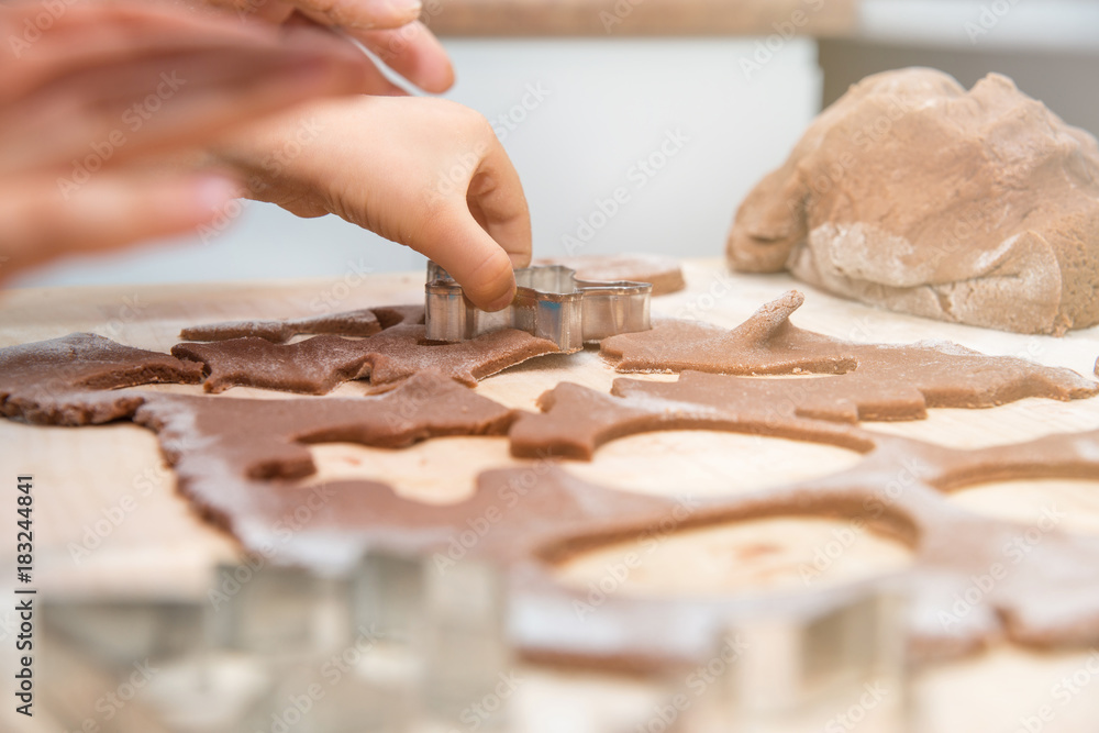 Baking gingerbreads. The family is preparing gingerbreads. The child is reflecting the mold in the dough. Preparing for Christmas, time for the family, cooking and baking together. Baking gingerbreads. The family is preparing gingerbreads. The child is reflecting the mold in the dough. Preparing for Christmas, time for the family, cooking and baking together.