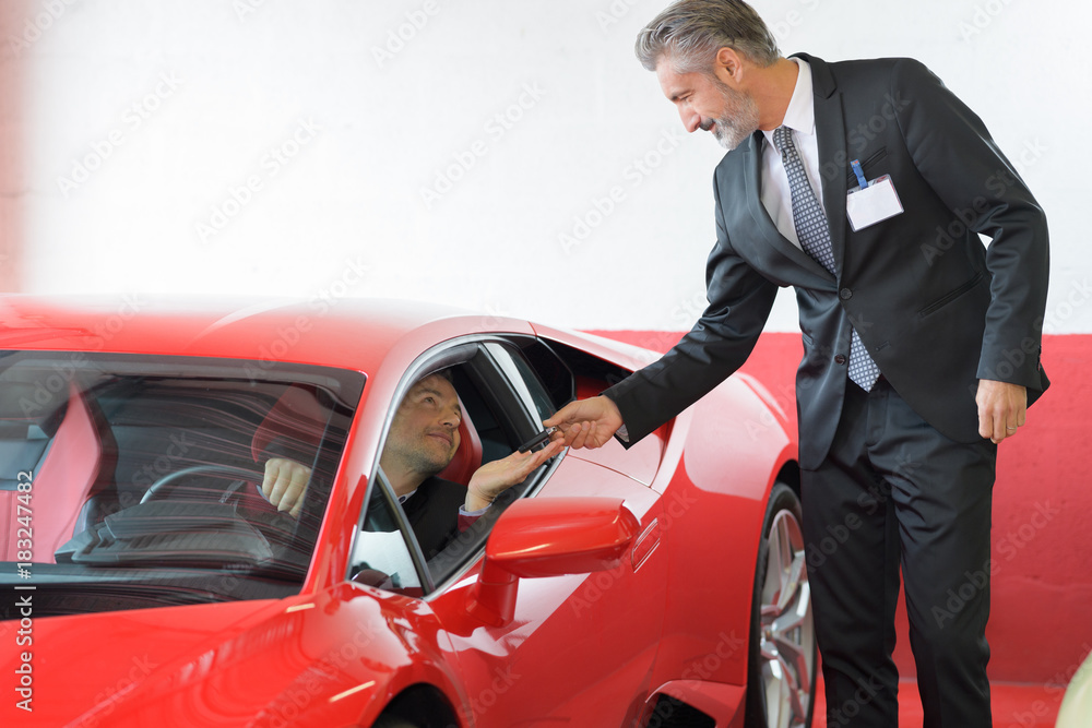 client and seller talking about lamborghini at luxury car dealer