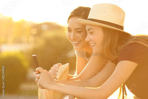 Two friends watching on line content at sunset