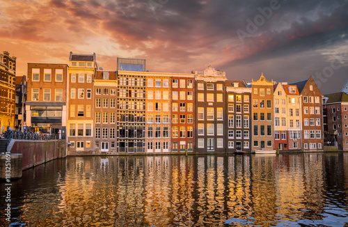 Traditional old buildings and boats at sunset in Amsterdam  Netherlands.