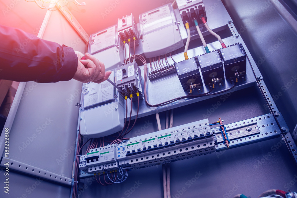 Electricians hands testing switches in electric box. Electrical panel