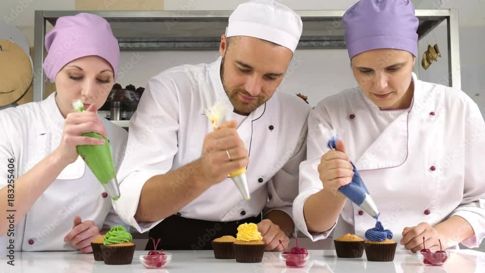 Decorating cup cake with cream. Confectioners making cupcakes for party Decorating cup cake with cream. Confectioners making cupcakes for party