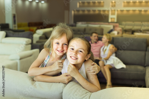 Two young sisters are pleased of new sofa © JackF