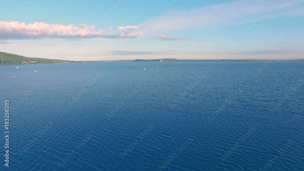AERIAL: A lot of seagulls fly over a huge lake on a sunny day. Beautiful nature scene with amazing landscape of endless water and pink clouds on the sky. AERIAL: A lot of seagulls fly over a huge lake on a sunny day. Beautiful nature scene with amazing landscape of endless water and pink clouds on the sky.