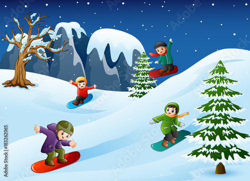 Happy kids in warm clothes snowboarding downhill
