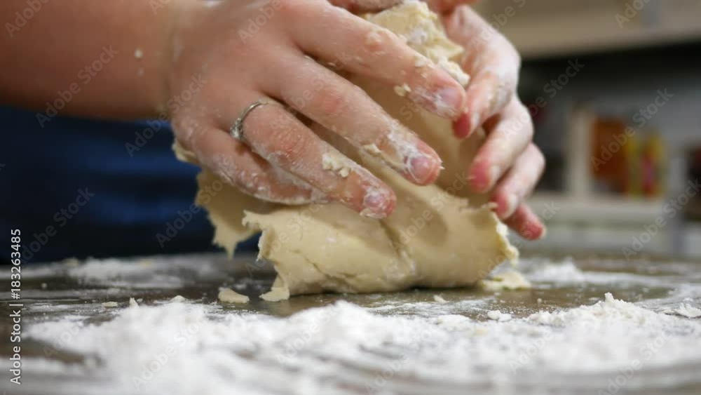 Woman kneading dough on kitchen counter and adding flour Woman kneading dough on kitchen counter and adding flour