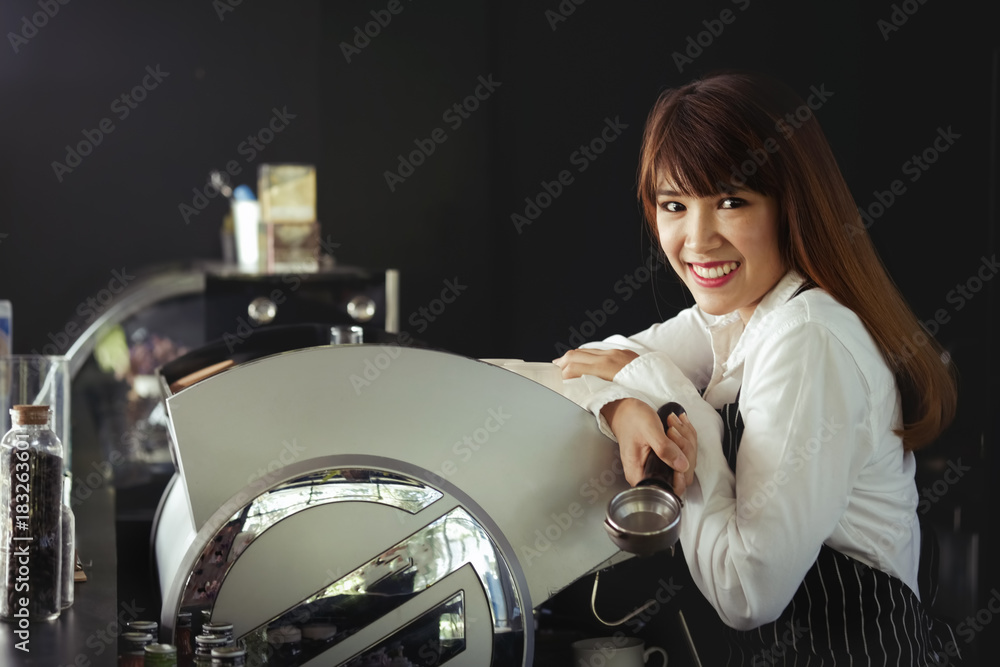 Confident barista. Young asian entrepreneur standing and holding Barista temper coffee behind her cafe counter.
