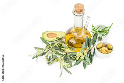 Glass bottle of premium virgin olive oil, avocado, rosemary and some olives with olive branch isolated on a white background
