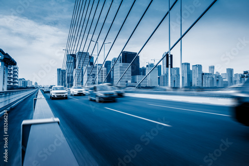 Traffic on modern bridge with skyline under blue sky