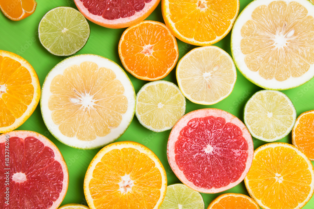 colored background of different citrus round lobules, on a green table